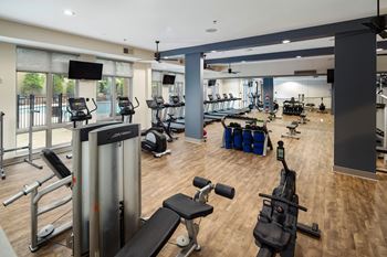 A gym with a variety of equipment including treadmills, weights, and exercise machines.